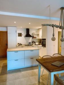 a kitchen with white cabinets and a wooden table at Casa Vista Bonita in Port de Soller