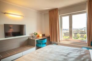 a hotel room with a bed and a television at Hotel Monaco Zeebrugge Beach in Zeebrugge