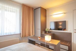 a bedroom with a bed and a desk and a television at Hotel Monaco Zeebrugge Beach in Zeebrugge