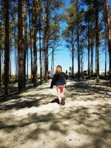 une femme se promenant sur un chemin de terre avec un scooter dans l'établissement Stilove Wydmy, à Sasino