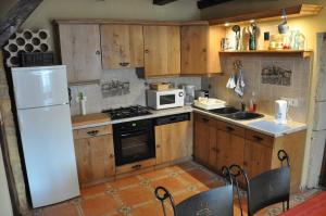 a kitchen with wooden cabinets and a white refrigerator at Logîte Touristique Les 3 Loups in Châtenois