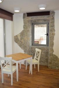 una mesa y sillas en una habitación con una pared de piedra en Vicencin place Downtown studio apartments, en Šibenik