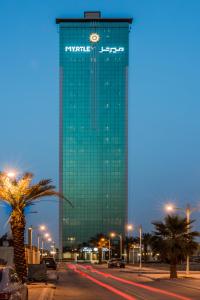 a tall green building with a clock on it at Myrtle Hotel - Al Sahafa in Riyadh