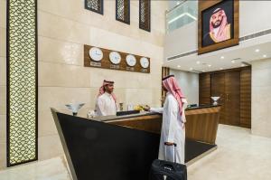 twee mensen staan aan een balie in een hotellobby bij Myrtle Hotel - Al Sahafa in Riyad
