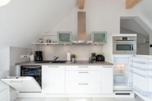 a white kitchen with white cabinets and appliances at Am Horizont No 2 Fewo für 4 Pers, 2 Schlafzimmer, Südbalkon, W-LAN, Homeoffice geeignet, Parkplatz in Zingst