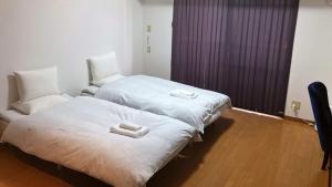 two beds in a hotel room with white sheets at THE LANG HOTEL Hakata in Fukuoka