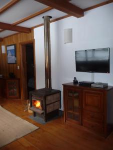 a fireplace in a living room with a stove at Cabaña La Cumeleña in Villa La Angostura