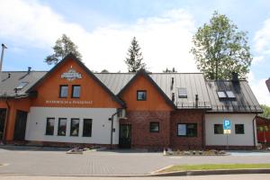 un bâtiment orange et blanc dans un parking dans l'établissement Azymut, à Suwałki