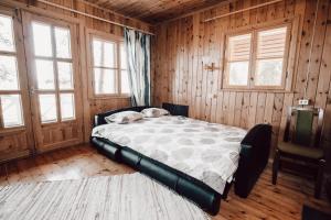 a bed in a room with wooden walls and windows at Ranniku Holiday House in Rannaküla
