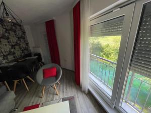 ein Wohnzimmer mit einem roten Kissen auf einem Stuhl und einem Fenster in der Unterkunft Apartments and Rooms Villa Majestic in Bihać