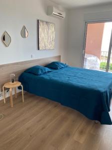 Un dormitorio con una cama azul y una mesa en Studio pieds dans l'eau, en Algajola