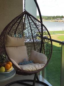 a hanging basket chair with pillows on a balcony at Lake and Spa Apartman in Velence