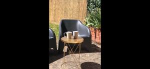 a black chair and a table with cups on it at Le studio d'Angèle : Angie in Bruz