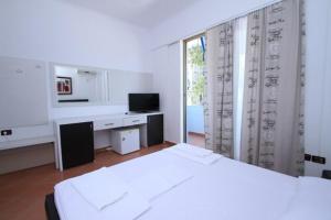 a white room with a bed and a desk and a window at Hotel Lepenica in Vlorë