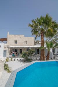a swimming pool in front of a house with a palm tree at Archetypo Villas and Suites in Naxos Chora