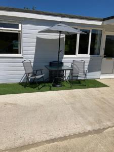 a table and chairs with an umbrella in front of a house at 8 Sandy Bottom Sandown Bay Holiday Park, reduced ferry, please contact us in Sandown