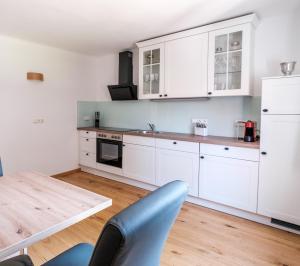 cocina con armarios blancos y mesa de madera en Ferienwohnung Hanna en Hatzendorf
