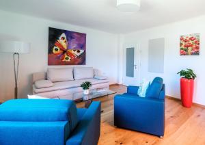 una sala de estar con sofás azules y una pintura de mariposas. en Ferienwohnung Hanna en Hatzendorf