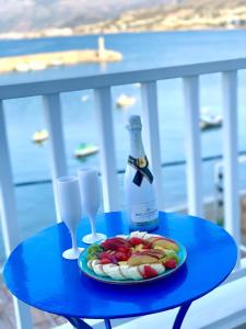 una mesa azul con una botella de vino y un plato de fruta en The Blue Apartments, en Hersonissos