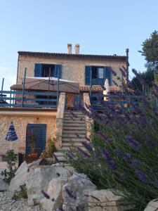 a house on the side of a hill with purple flowers at La casa dalle finestre blu in Abbateggio