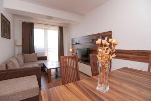 uma sala de estar com uma mesa de madeira com um vaso de flores em Apartmany Sileas em Veľká Lomnica