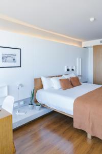 1 dormitorio con 1 cama blanca grande y escritorio en Opta Coliving Punta Carretas, en Montevideo
