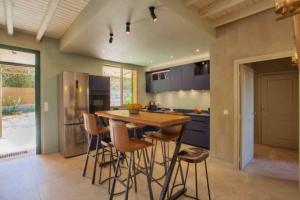 cocina con mesa de madera y taburetes en Villa La Giraudière en Calvi