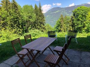 a wooden picnic table and two chairs with mountains in the background at Petite Marmotte in Saint-Gervais-les-Bains +9 photos
