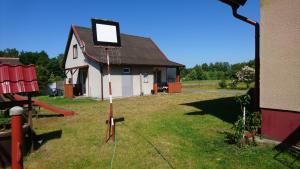 a small house with a sign in the yard at Dom Bursztynek - domek murowany in Junoszyno