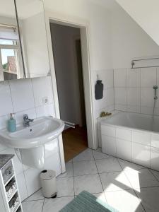 a white bathroom with a sink and a tub at Ferienwohnung Mühlendamm in Bergen +14 photos