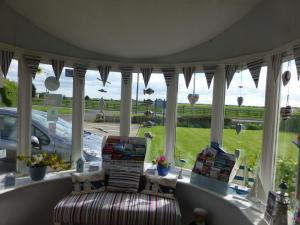 a screened in porch with a couch and windows at The Ramblers in Trusthorpe