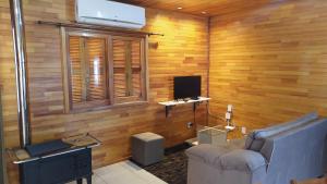 sala de estar con paredes de madera, sofá y TV en Apartamento Serrano 2 en São Joaquim
