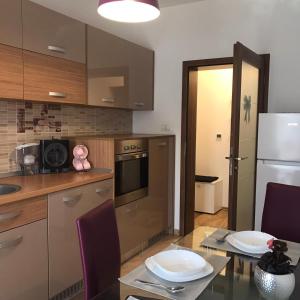 a kitchen with a table and a white refrigerator at Paula Apartment in Dumbrăviţa