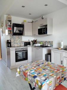 una cocina con armarios blancos y una mesa. en Charmant studio Bord de mer Plage Ste Marguerite Pornichet en Pornichet