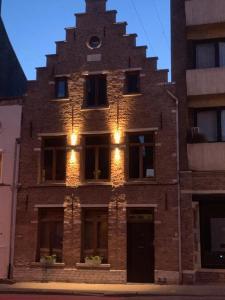 un grand bâtiment en briques avec des lumières sur lui dans l'établissement BnB De Koepoort, à Malines