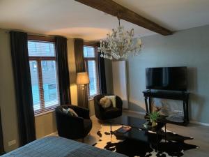 - un salon avec un lit, deux chaises et un lustre dans l'établissement BnB De Koepoort, à Malines