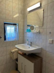 un bagno con un lavandino bianco e uno specchio di Ferienwohnungen Rasinger a Schiefling am Wörthersee Altre 28 foto