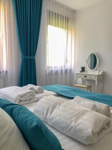 a bedroom with two beds with blue curtains and a window at Gizell Apartment 1 in Sibiu