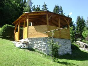 a wooden gazebo in a grassy field with a building at Penzion 358 in Vrchlabí