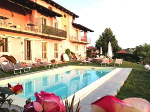 a swimming pool in front of a house with pink flowers at Domus Langhe B&B in Treiso