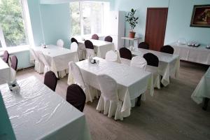 ein Zimmer mit weißen Tischen und Stühlen in einem Zimmer in der Unterkunft Altai Business Hotel in Almaty