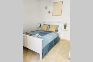 um quarto com uma cama branca com almofadas azuis e amarelas em UIM Mediterraneo Poeta 1 Wifi em Puerto de Sagunto