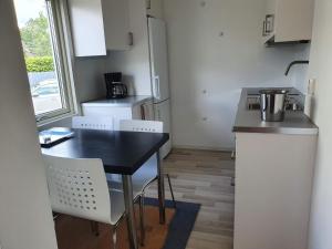 una pequeña cocina con mesa negra y sillas blancas en Centralt i Falkenberg, en Falkenberg