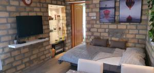 um quarto com uma parede de tijolos, uma cama e uma televisão em Bakina kuća em Golubac