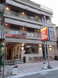 a hotel with a sign in front of a building at Hotel Strimoniko in Asprovalta