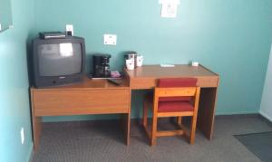 a desk with a television and a coffee table at Motel Royal in Cabano