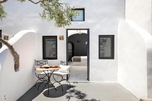 a white house with a table and chairs in front of a door at Pearl of Caldera Oia - Boutique Hotel by Pearl Hotel Collection in Oia