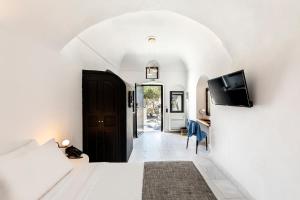 a bedroom with a bed and a tv on a wall at Pearl of Caldera Oia - Boutique Hotel by Pearl Hotel Collection in Oia