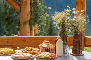a table with plates of food and vases with flowers at Sustainable Samel's Cottage Hrid's lake Prokletije in Plav