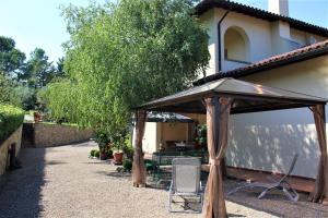 un patio con ombrellone e sedia di fronte a una casa di Casa le Betulle a Montespertoli